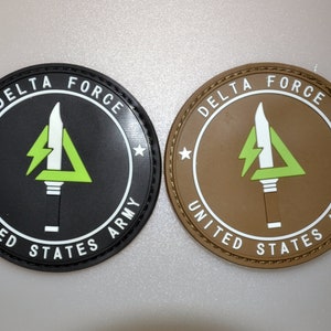 May include: Two circular patches with the text "DELTA FORCE" and "UNITED STATES ARMY". One is black with white text and a green and white emblem. The other is brown with white text and a green and white emblem.