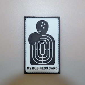 May include: A rectangular patch with a black border and a white background. The patch features a black target silhouette with concentric rings and numbers. The text "MY BUSINESS CARD" is printed at the bottom.