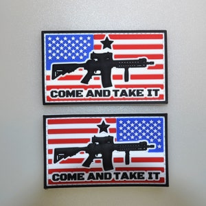 May include: Two rectangular patches featuring the American flag design with a black rifle silhouette overlaid. The patches have a blue field of stars, red and white stripes, and the text "COME AND TAKE IT" in white.