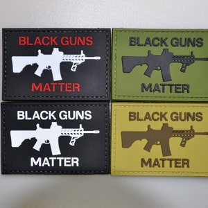 Könnte beinhalten: Vier rechteckige Aufnäher mit dem Text "BLACK GUNS MATTER" und einer Gewehrgrafik. Die Aufnäher sind schwarz, grün und beige, mit Text und Gewehr in kontrastierenden Farben. Die Aufnäher sind wahrscheinlich für taktische Ausrüstung.