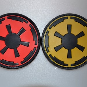 May include: Two circular patches with a black and red design and a black and yellow design. The patches have a black border and a central starburst pattern. The patches are likely related to a science fiction theme.