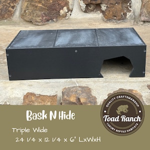 K&ouml;nnte beinhalten: Schwarzes Reptilienhabitat mit einer gro&szlig;en &Ouml;ffnung f&uuml;r eine Versteckm&ouml;glichkeit. Das Habitat ist aus Holz und hat eine strukturierte Oberfl&auml;che. Das Habitat ist mit "Bask N Hide Triple Wide 24 1/4 x 12 1/4 x 6" LxWxH" beschriftet.
