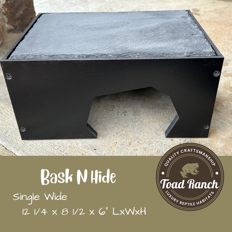 K&ouml;nnte beinhalten: Schwarze Reptilien-H&ouml;hle mit Schieferplatte. Die H&ouml;hle ist 31,1 cm lang, 21,6 cm breit und 15,2 cm hoch. Die H&ouml;hle ist mit "Bask N Hide Single Wide" beschriftet.