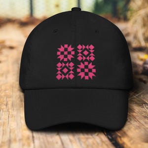 May include: A black baseball cap with a pink embroidered geometric pattern. The pattern is made up of four squares, each with a different design.