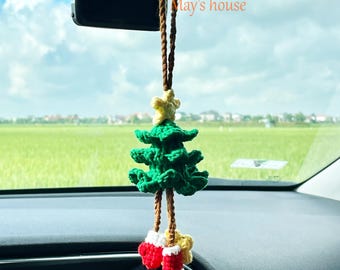 May include: A crocheted Christmas tree car charm. The green tree has a yellow star and red stockings. It hangs from a brown string. The text "May's house" is visible in the background. The time on the car's display reads 8:40.