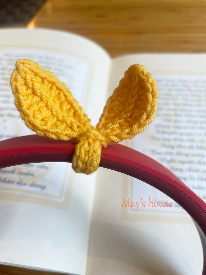 May include: Yellow crocheted bunny ear shaped headphone covers on a red headband. The text "May's house" is visible in the background.