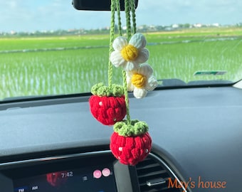 May include: A handmade car charm featuring two red crocheted strawberries with green tops and two white daisy flowers with yellow centers. The charm hangs from a green crocheted cord. The text "May's house" is visible.