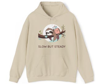 May include: Beige hoodie with a front pocket and drawstring hood. The front features a graphic of a sloth on a branch with a coffee cup and backpack, and the text "SLOW BUT STEADY".