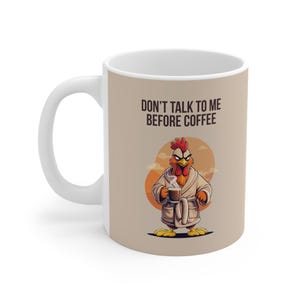Könnte beinhalten: Weiße Keramik-Kaffeetasse mit einem Cartoon-Huhn im Bademantel, das eine Kaffeetasse hält. Auf der Tasse steht der Text "DON'T TALK TO ME BEFORE COFFEE". Das Design zeigt eine humorvolle Darstellung eines Morgenrituals.