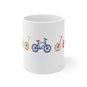 May include: White ceramic mug with a colorful design of four bicycles. The bicycles are in a row, with the front wheel of each bicycle touching the back wheel of the bicycle in front of it. The bicycles are in the colors red, yellow, blue, and green.