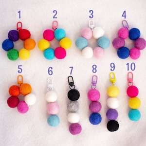 May include: Ten colorful felt ball keychains with different color combinations. Each keychain has a metal ring and a small metal hook.