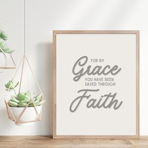 May include: A framed print with a white background and gray text that reads "For by Grace you have been saved through Faith".