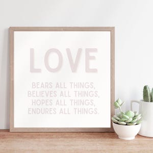 May include: A framed print with the word "LOVE" in large, pink letters. The text below reads "Bears all things, Believes all things, Hopes all things, Endures all things."