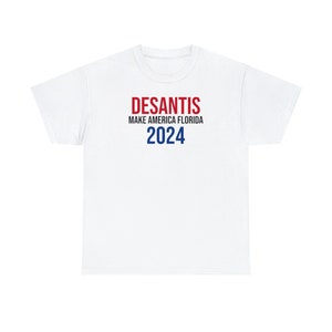 May include: White t-shirt with red and blue text that reads "DESANTIS MAKE AMERICA FLORIDA 2024".