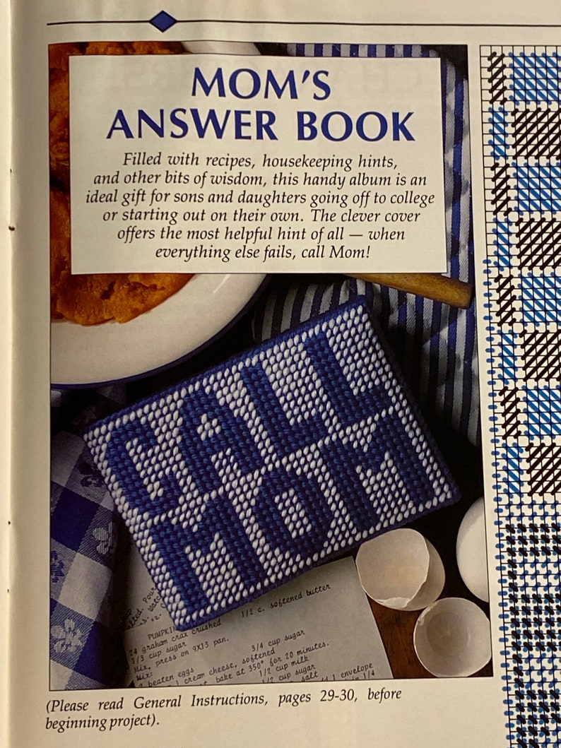 May include: A blue and white needlepoint project with the words "Call Mom" stitched in white. The project is sitting on a white and blue checkered fabric. The text "Please read General Instructions, pages 29-30, before beginning project." is printed below the project.