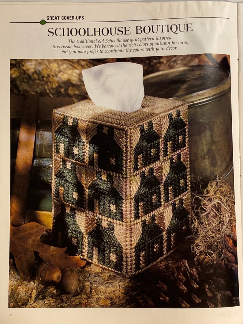 May include: A green and brown tissue box cover with a schoolhouse pattern. The cover is made of fabric and has a quilted design. The text "SCHOOLHOUSE BOUTIQUE" is printed on the cover.