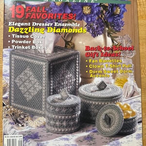 May include: A magazine cover titled "Plastic Canvas!" features a still life of gray and white plastic canvas creations, including a tissue box and trinket boxes. The cover also displays text: "19 Fall Favorites!" and "Back-to-School Gift Ideas!"