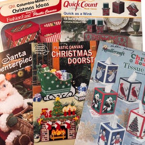 May include: A collection of five instructional craft booklets featuring plastic canvas projects. The covers display various holiday-themed designs including tissue box covers, a Santa centerpiece, a fireplace, and a sleigh, all with colorful patterns.