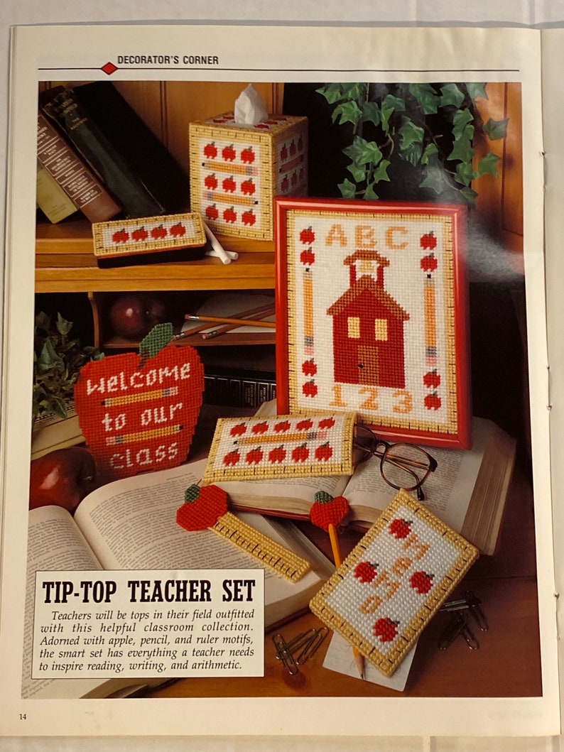 May include: A set of five red and yellow canvas needlepoint crafts with an apple theme. The set includes a tissue box cover, a pencil holder, a ruler, a small box, and a framed picture. The picture features a red schoolhouse with the letters ABC and the numbers 123. The pencil holder has the words "Welcome to our class".