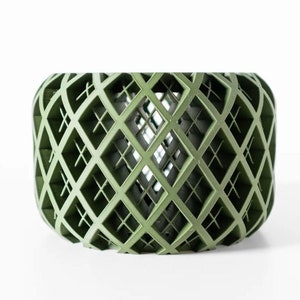 May include: A green, geometric, cylindrical vase with a lattice design. The vase is made of a lightweight material and has a hollow center.