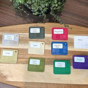 May include: A set of ten color swatches, each with a different color and a label. The colors include: Olive Green, Magenta, Glow in Dark, Khaki, Sand, Egyptian Blue, White, Purple, Light Olive, and True Green.