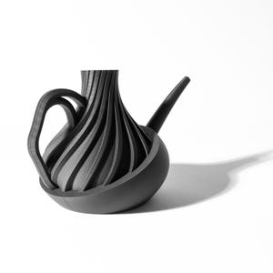 May include: A black watering can with a unique, swirling design. The spout is long and curved, and the handle is attached to the side of the can.