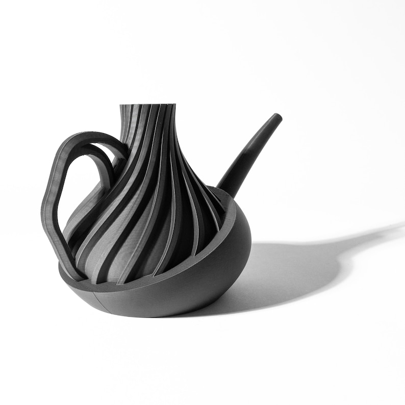 May include: A black watering can with a unique, swirling design. The spout is long and curved, and the handle is attached to the side of the can.