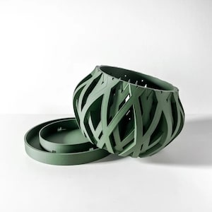 May include: A green planter with a geometric design. The planter has a removable inner pot.