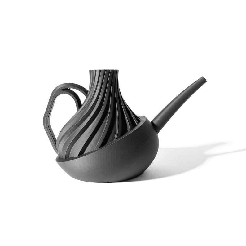May include: A black watering can with a unique, swirling design. The spout is long and curved, and the handle is attached to the side of the can.