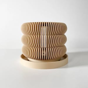 May include: A beige, wooden planter with a unique, wavy design. The planter has a removable base and is perfect for displaying plants or flowers.