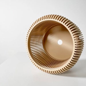 May include: A beige, round, decorative planter with a slatted design. The planter has a hole in the bottom for drainage.