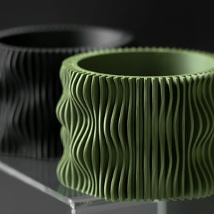 May include: Two decorative planters, one black and one green. Both planters have a wavy, textured design.