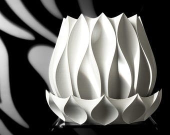May include: A white ceramic vase with a unique, organic design. The vase has a wide, rounded base and a narrow opening at the top. The surface of the vase is textured with a series of overlapping, petal-like shapes.