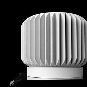 May include: A white, cylindrical object with vertical, curved grooves. The object sits on a white base against a black background. The design is minimalist and modern, with a focus on texture and form.