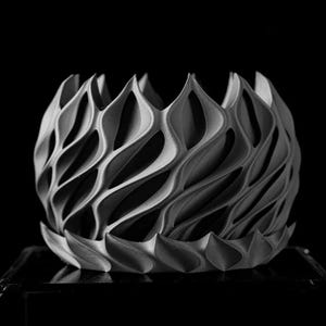 May include: A gray, 3D printed, decorative object with a geometric, wave-like pattern. The object is shaped like a bowl or a vase.