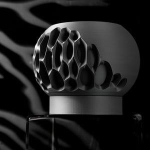 May include: A gray ceramic diffuser with a geometric pattern. The diffuser has a round top and a cylindrical base.