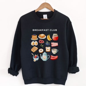 May include: Black sweatshirt with a white graphic of breakfast foods and the text "Breakfast Club".