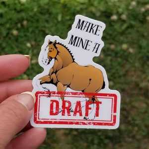 May include: A white sticker with a brown and white horse illustration. The horse is standing on its hind legs with its front legs raised. The sticker says "Make Mine a Draft" in black text with a red stamp around the words "Draft".