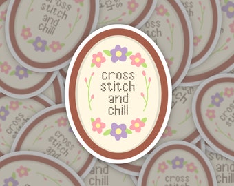 Puede incluir: Una pila de pegatinas redondas con un borde marrón y un fondo crema. Las pegatinas presentan un diseño de punto de cruz con el texto "cross stitch and chill" rodeado de flores rosas y moradas.