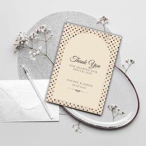 May include: A rectangular thank you card featuring a cream-colored center with an arched design, surrounded by a border of small brown and gold polka dots. The text reads Thank You FOR SHARING OUR SPECIAL DAY RACHEL & SIMON 08.08.2026.