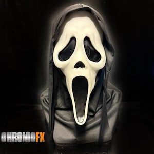 Op de afbeelding: Een Scream-masker met een wit gezicht, zwarte oogopeningen en een open mond. Het masker staat tegen een zwarte achtergrond en wordt omlijst door een zwarte kap. De tekst "CHRONICFX" is onderaan zichtbaar.