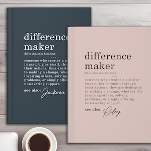 Könnte beinhalten: Zwei Notizbücher, eines rosa und eines blau, mit der Definition des Wortes "difference maker" darauf gedruckt. Die Definition enthält die phonetische Schreibweise des Wortes und den Text "siehe auch:" gefolgt von einem Namen. Der Name auf dem rosa Notizbuch ist Riley und der Name auf dem blauen Notizbuch ist Jackson.