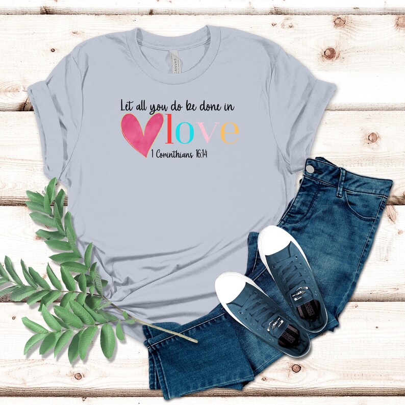 May include: Light blue t-shirt with the text "Let all you do be done in love" and a pink heart. The text "1 Corinthians 16:14" is also on the shirt.