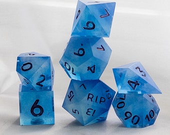 May include: A set of six blue dice with white numbers. The dice are arranged in a pyramid shape, with the top die showing a 9, the next die down showing a 6, the next die down showing a 2, the next die down showing a 4, the next die down showing a 13, and the bottom die showing a 10.