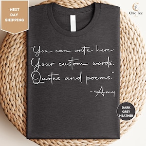 a gray t-shirt with a quote printed on it, placed on a woven mat.