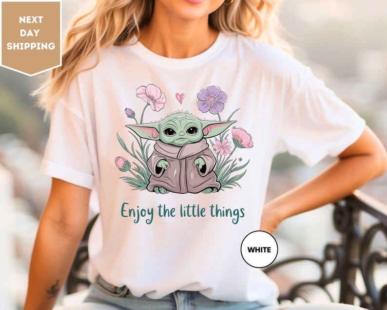 a woman wearing a white t - shirt with a picture of a baby yoda