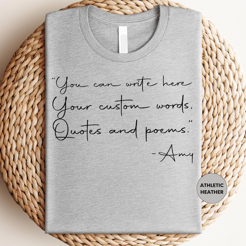 A gray t-shirt with a quote printed on it, placed on a woven mat.