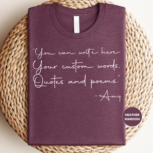 a purple t-shirt with a quote printed on it, placed on a woven mat.