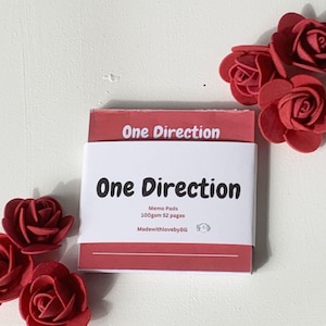 Puede incluir: Bloc de notas rojo con el texto "One Direction" en la parte delantera. El bloc de notas es de 100 g/m² y tiene 52 páginas. El texto "MadewithlovebyBG" también está en la parte delantera del bloc de notas.