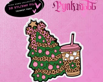 May include: A 3D STL/3MF file for a trinket tray featuring a green Christmas tree decorated with pink ornaments, stars, and a leopard print bow, alongside a pink-lidded iced coffee cup with a leopard print sleeve and a green flower.